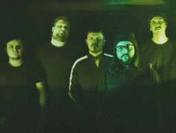 Die Blackend Hardcore Band Vaataja aus Langen, zu fünft in grünem Licht stehend