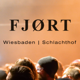 Schriftzug: FJØRT, darunter Wiesbaden | Schlachthof. Im Bild zu sehen sind Köpfe im Zuschauerraum mit orangenen Licht