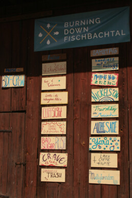 das Festival-LineUp in bunter Schrift auf Holztafeln