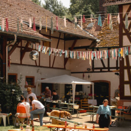 Ein Hof mit Fachwerkhäusern und bunten Fähnchen