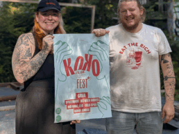 Hannah und Julius halten das Plakat hoch für das Jubiläumsfest des Konglomerat Kollektivs