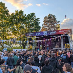 Bunde Fahnen und eine große Menschenmenge vor einer Bühne auf dem Raus ausm Keller Festival Egelsbach