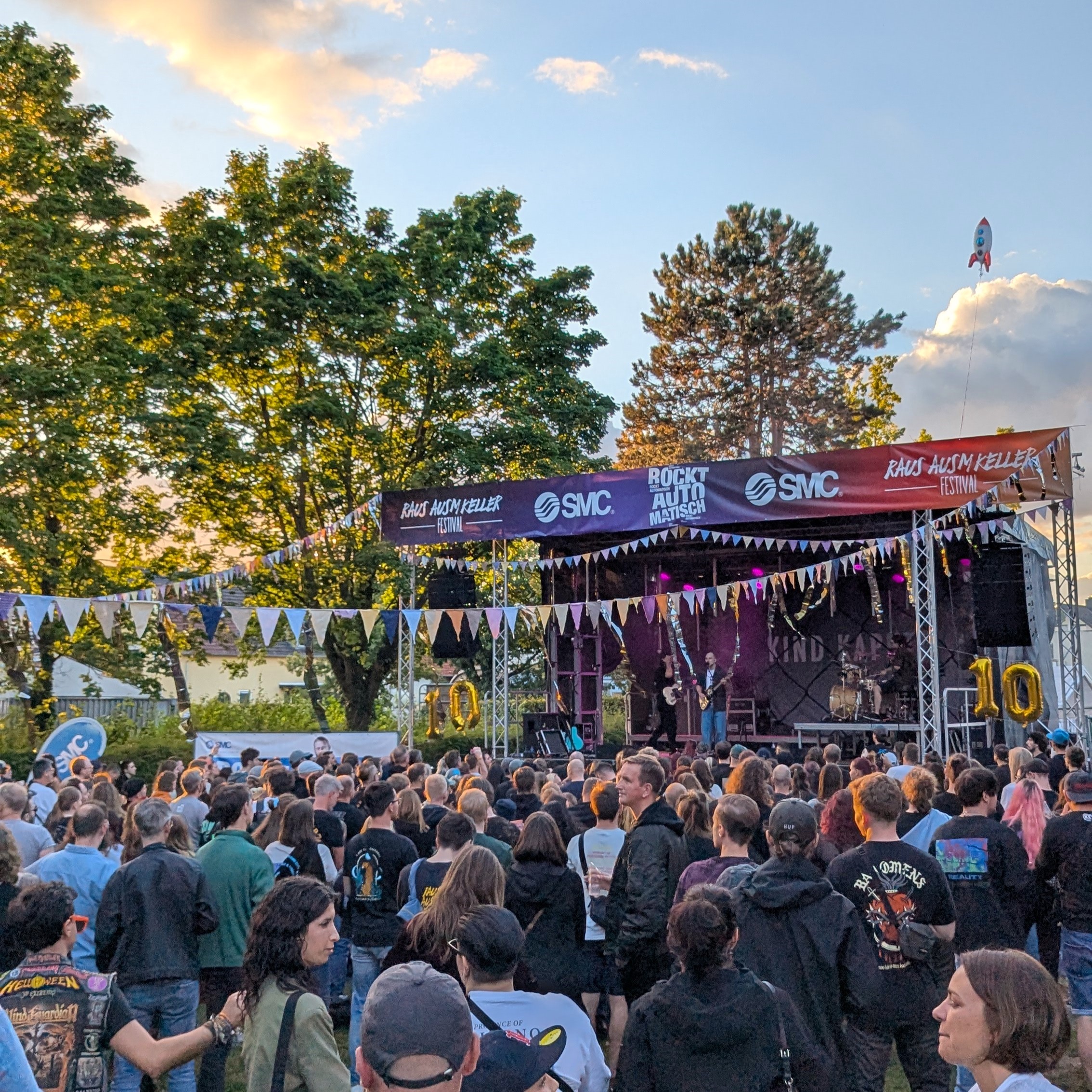 Bunde Fahnen und eine große Menschenmenge vor einer Bühne auf dem Raus ausm Keller Festival Egelsbach