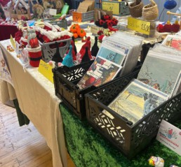 Boxen auf einem Tisch gef&uuml;llt mit laminierten Bildern, daneben geh&auml;kelte Weohnachtwichtel